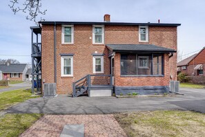 Un bâtiment à deux étages, construit en briques, avec un porche avant couvert, un escalier et une grande fenêtre.