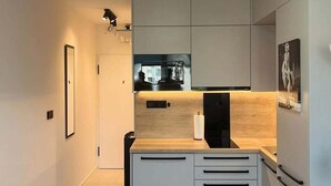 A modern kitchen with a central island, built-in appliances, and a recessed ceiling light. - Beautiful 1-bedroom apartment in cozy Košický kraj perfect for relaxing (Košický kraj)