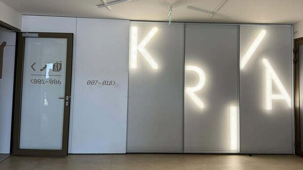 A modern interior with a large illuminated 'KRY' sign, a door with a number, and a sofa. - Beautiful 1-bedroom apartment in cozy Košický kraj perfect for relaxing (Košický kraj)