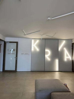 A modern interior with a large illuminated 'KRY' sign, a door with a number, and a sofa.