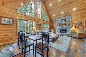 A log cabin interior with a dining area, sofa, fireplace, and large windows. - 1 Mi to Cle Elum Lake! Family Cabin w/ Game Room (Cle Elum)