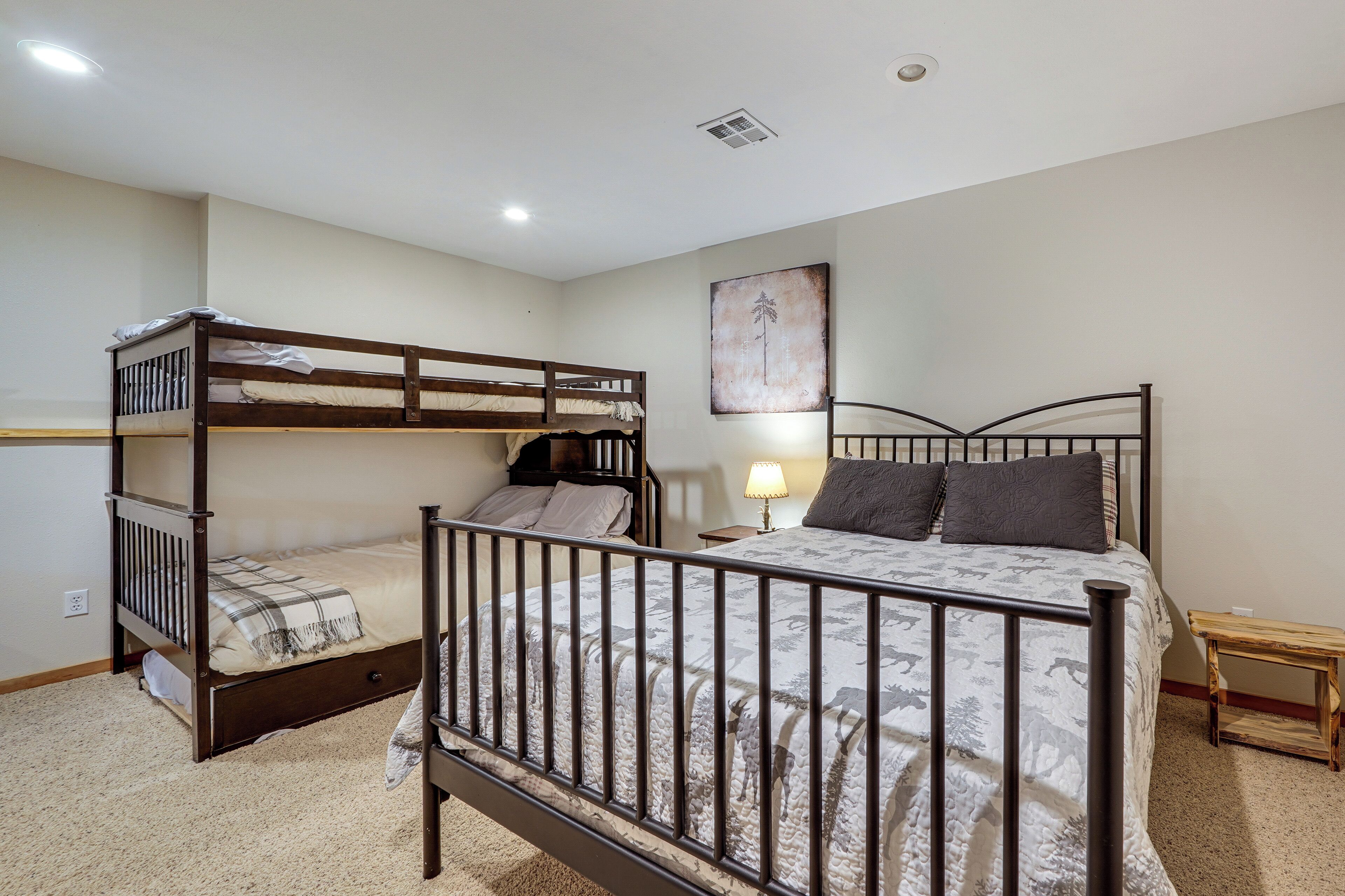 Un dormitorio con literas, una mesita de noche con lámpara y un cuadro en la pared.