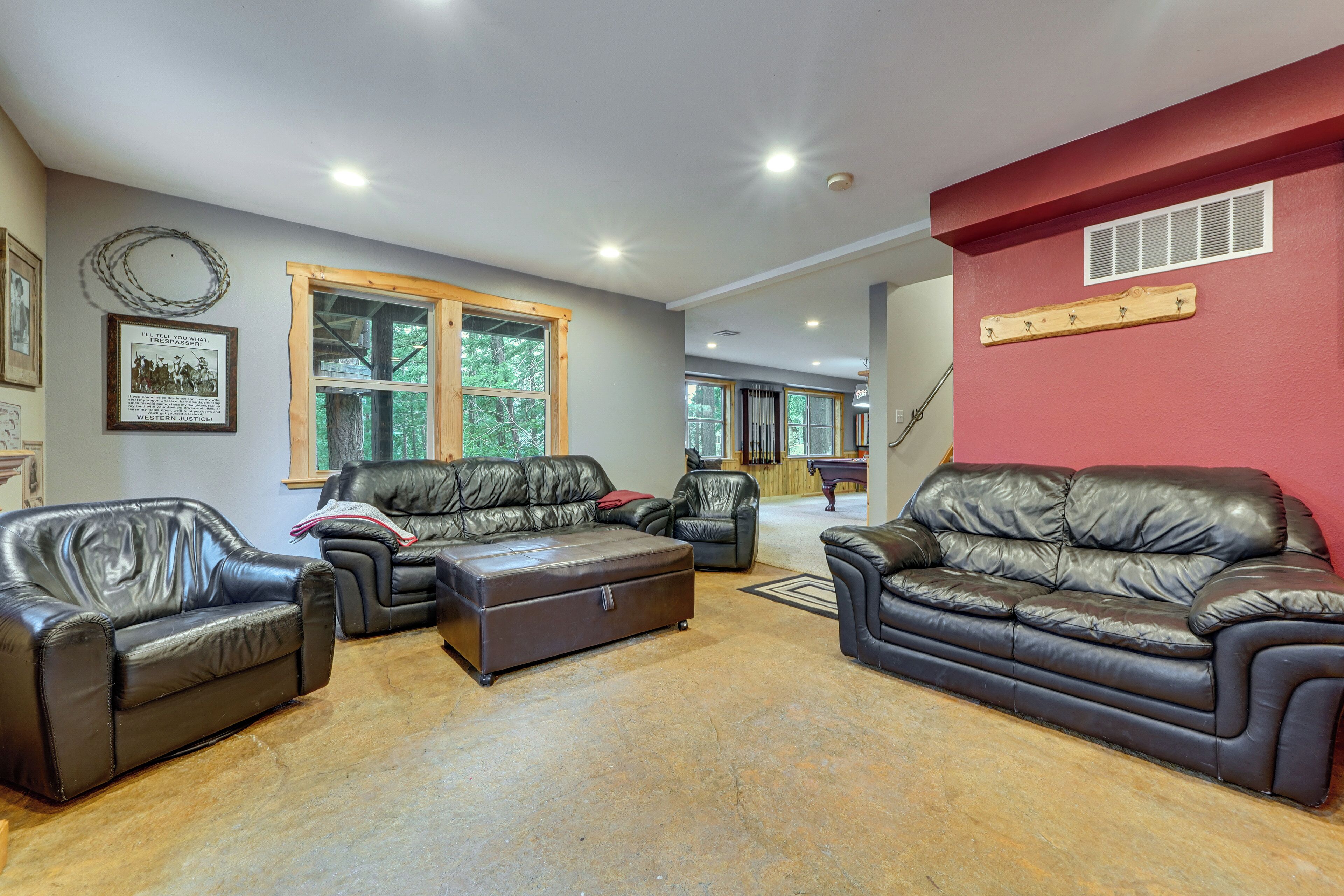 A spacious living room with leather sofas, a wooden coffee table, and a red accent wall.
