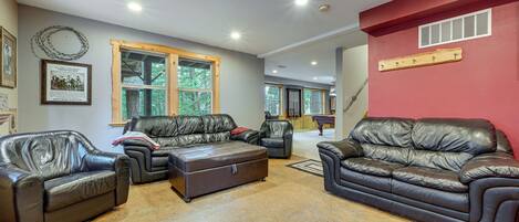 A spacious living room with leather sofas, a wooden coffee table, and a red accent wall.