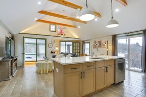 A spacious kitchen with wooden cabinets, a central island, and a large window providing a view of the outdoors. - Lakeside Charm! Updated Home Near Mtn Creek Resort (West Milford)