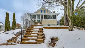 Ein zweigeschossiges Haus mit verschneitem Vorgarten und einer Treppe, die zum Eingang führt.