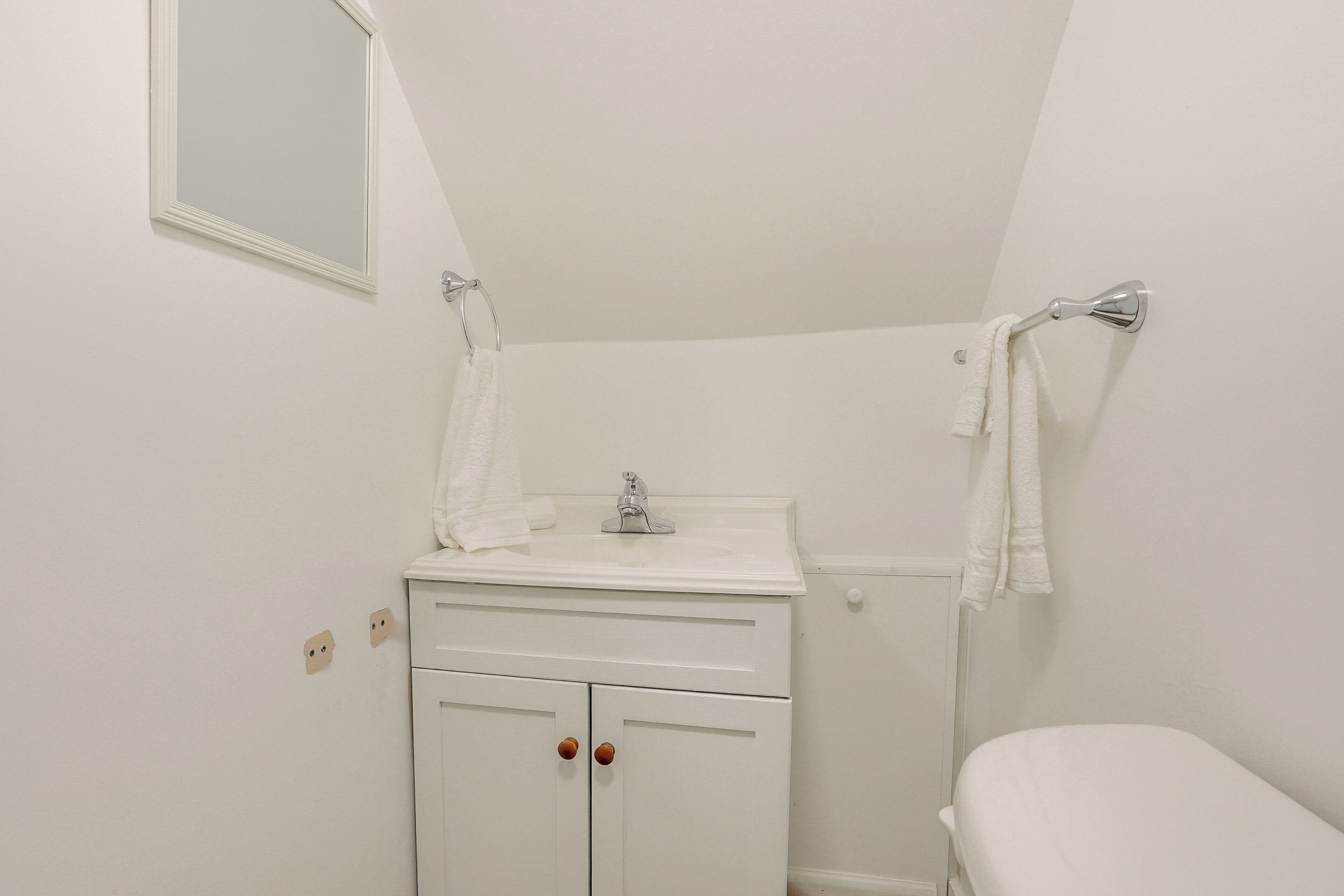 A small bathroom with a white sink, mirror, and toilet.