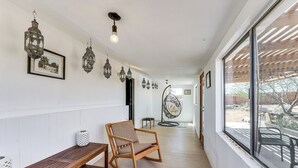 Ein Flur mit einer hölzernen Bank, einem Schaukelstuhl, hängenden Laternen und einem großen Fenster mit Blick.