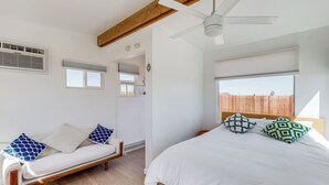 Ein Schlafzimmer mit Bett, Sitzbank und Deckenventilator.