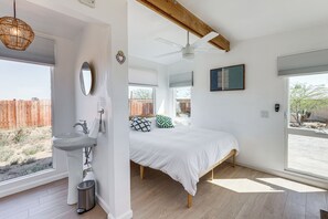 Un dormitorio con cama, lavamanos, espejo y ventilador de techo.