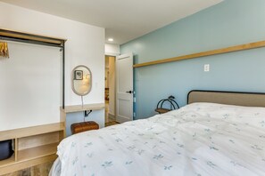 A bedroom with a bed, a bedside table, a mirror, a hanging light fixture, and a wardrobe.