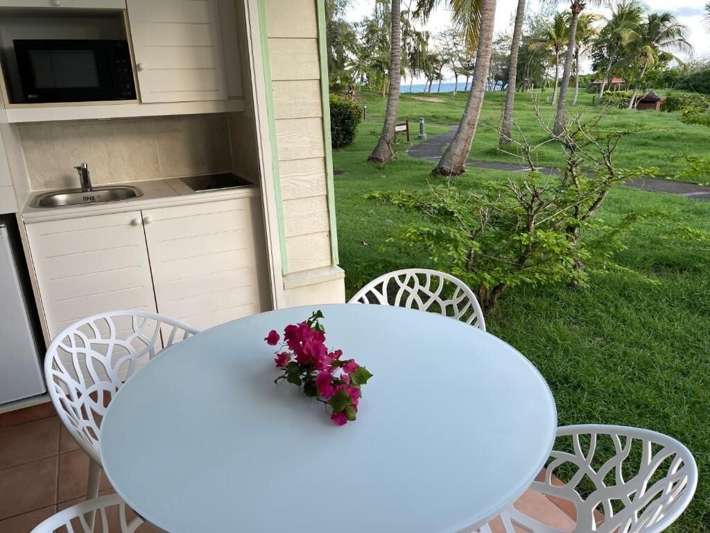 Una cocina con microondas, lavamanos y zona de comedor con mesa y sillas.