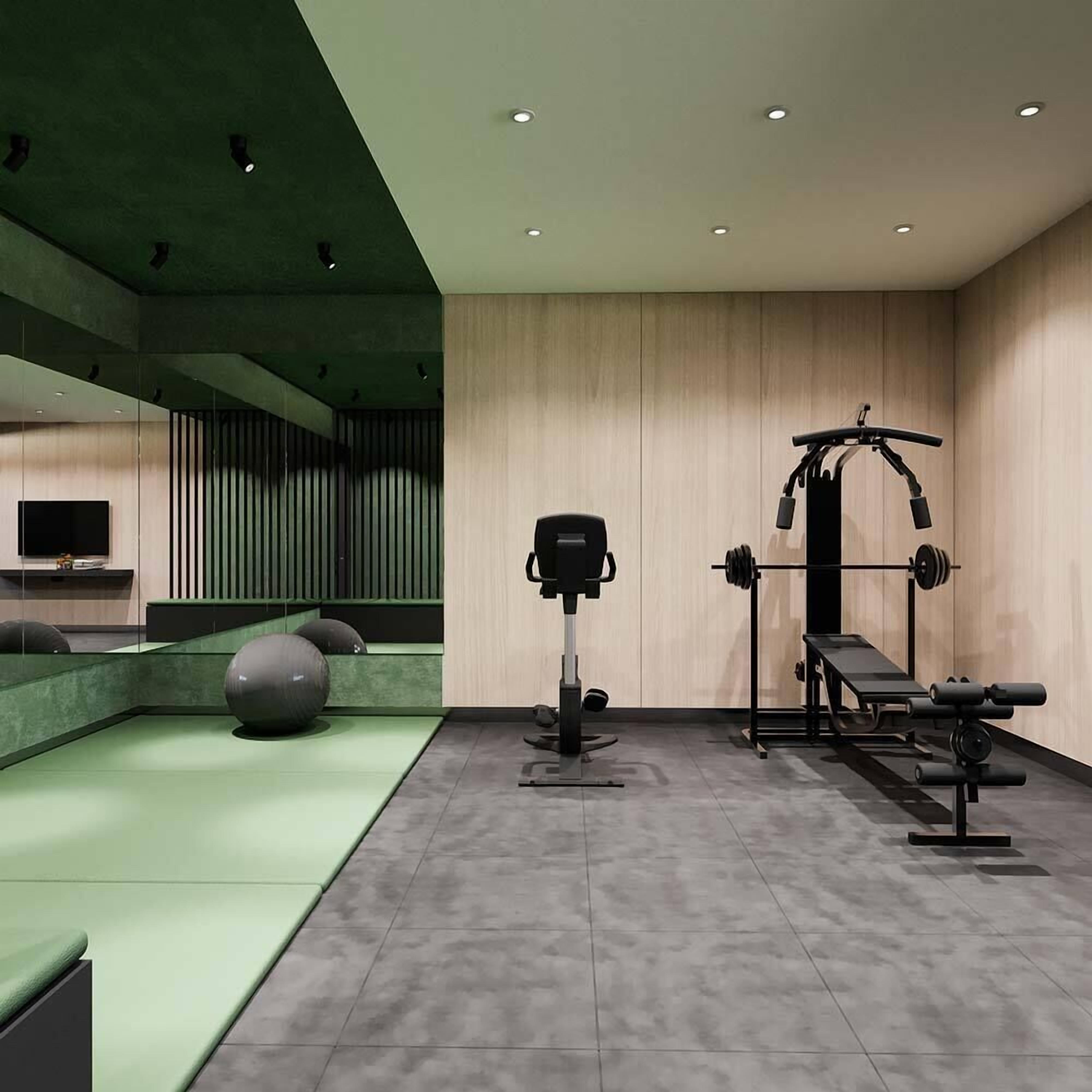 A gym with exercise equipment, a TV, and a green cushioned area.
