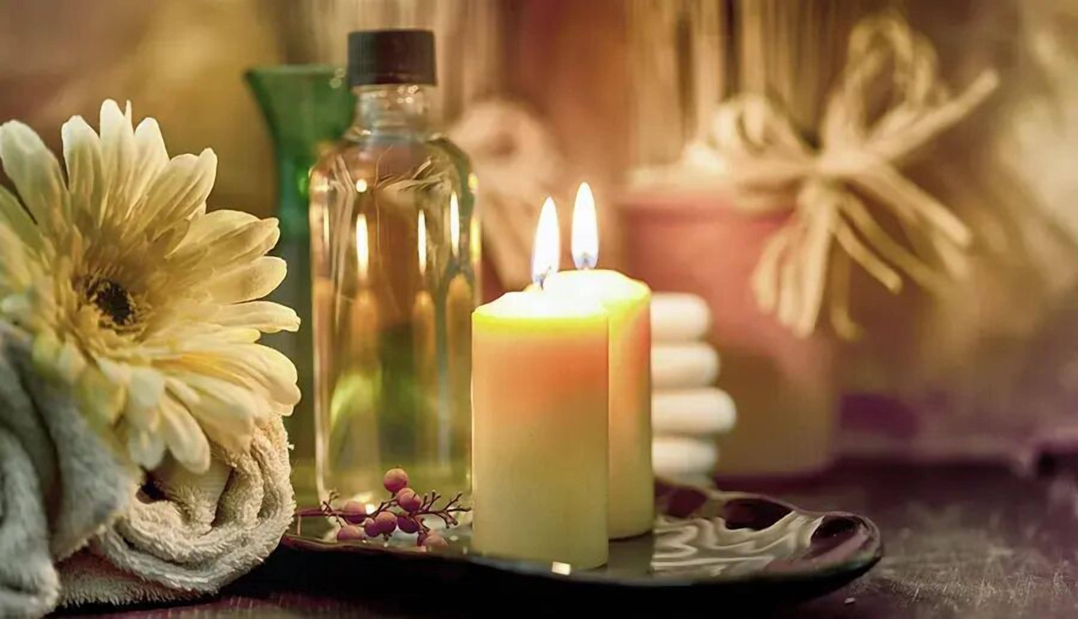 Une bougie, une bouteille et une fleur sur un plateau.
