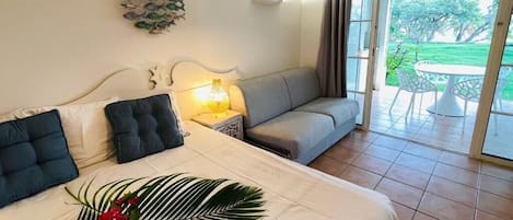 Habitación de hotel con cama, sofá, mesa, lámpara y vistas al exterior.