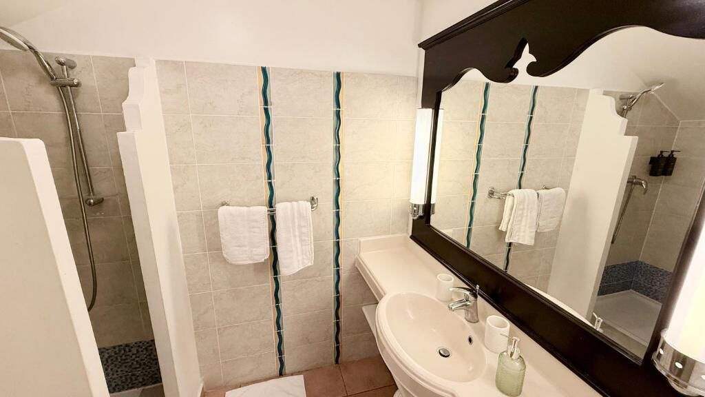 A bathroom with a shower, a sink, a mirror, and towels.