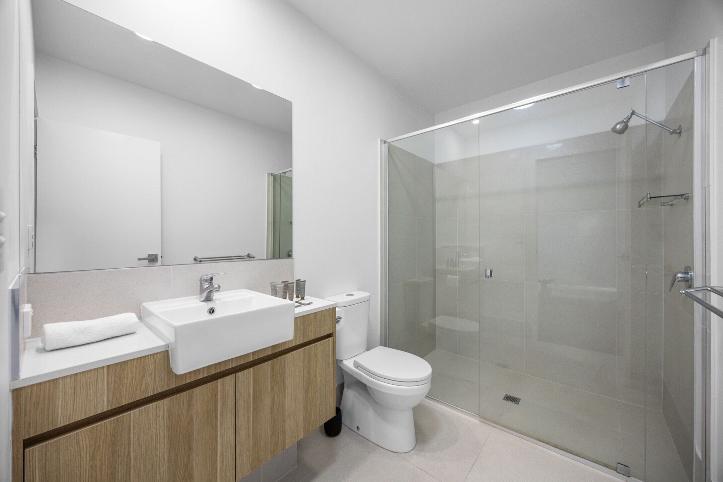 A modern bathroom with a glass-enclosed shower, a white sink, and a toilet.