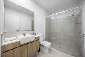 Un bagno moderno con doccia vetrata, lavandino bianco e water.