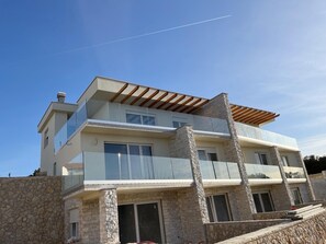 Ein modernes, zweistöckiges Haus mit Steinverkleidung, großen Fenstern und einem Balkon.
