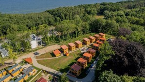 A row of yellow buildings with red roofs, surrounded by greenery and a body of water. - Comfortable Holiday Home , Summer Pool (Rewal)