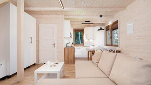 A modern interior with a wooden ceiling, a sofa, a dining table, and a kitchen area. - Comfortable Holiday Home , Summer Pool (Rewal)