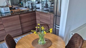 Una cocina moderna con armarios de madera, una mesa redonda con sillas y un florero con flores.