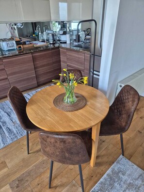 Eine moderne Küche mit Holzausstattung, einem runden Esstisch mit Stühlen und einer Vase mit Blumen.