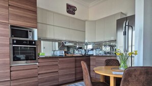 Una cocina moderna con electrodomésticos integrados, un comedor con una mesa redonda y sillas, y una isla de cocina.