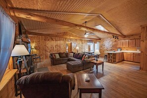 Ein Holzblockhaus-Interieur mit Wohnzimmer, Essbereich und Küche.