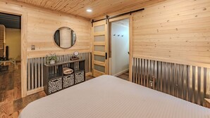 Ein Schlafzimmer mit einem Bett, einem Spiegel, einem Holzschrank und einer Schiebetür.