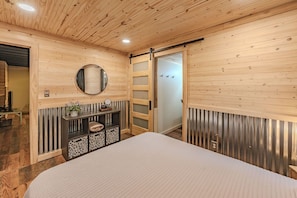 Ein Schlafzimmer mit einem Bett, einem Spiegel, einem Holzschrank und einer Schiebetür.