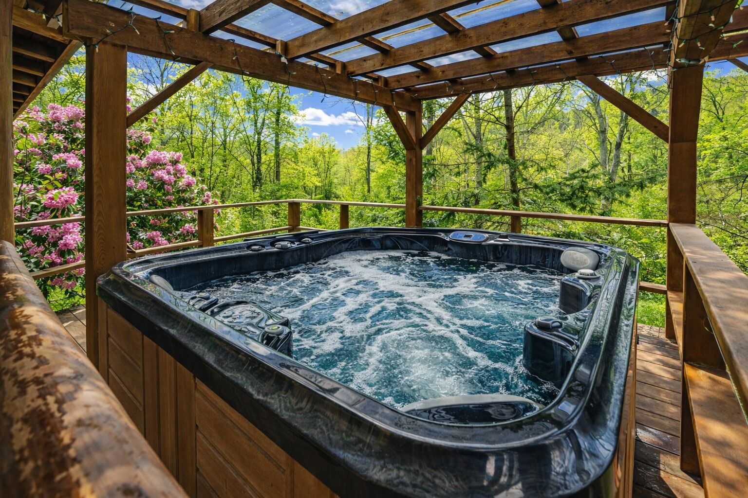 A hot tub in a wooden gazebo with a view of trees and flowers.