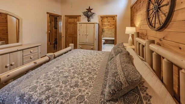 Une chambre à coucher avec un lit, des murs en bois, un ventilateur de plafond, une armoire en bois et une grande roue en bois accrochée au mur.