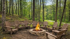 Un feu de camp entouré de chaises Adirondack en bois, le tout situé dans un cadre forestier.