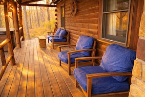 Eine Holzterrasse mit einer Reihe Holzstühle und einer Bank, eine Steinmauer und ein Fenster.