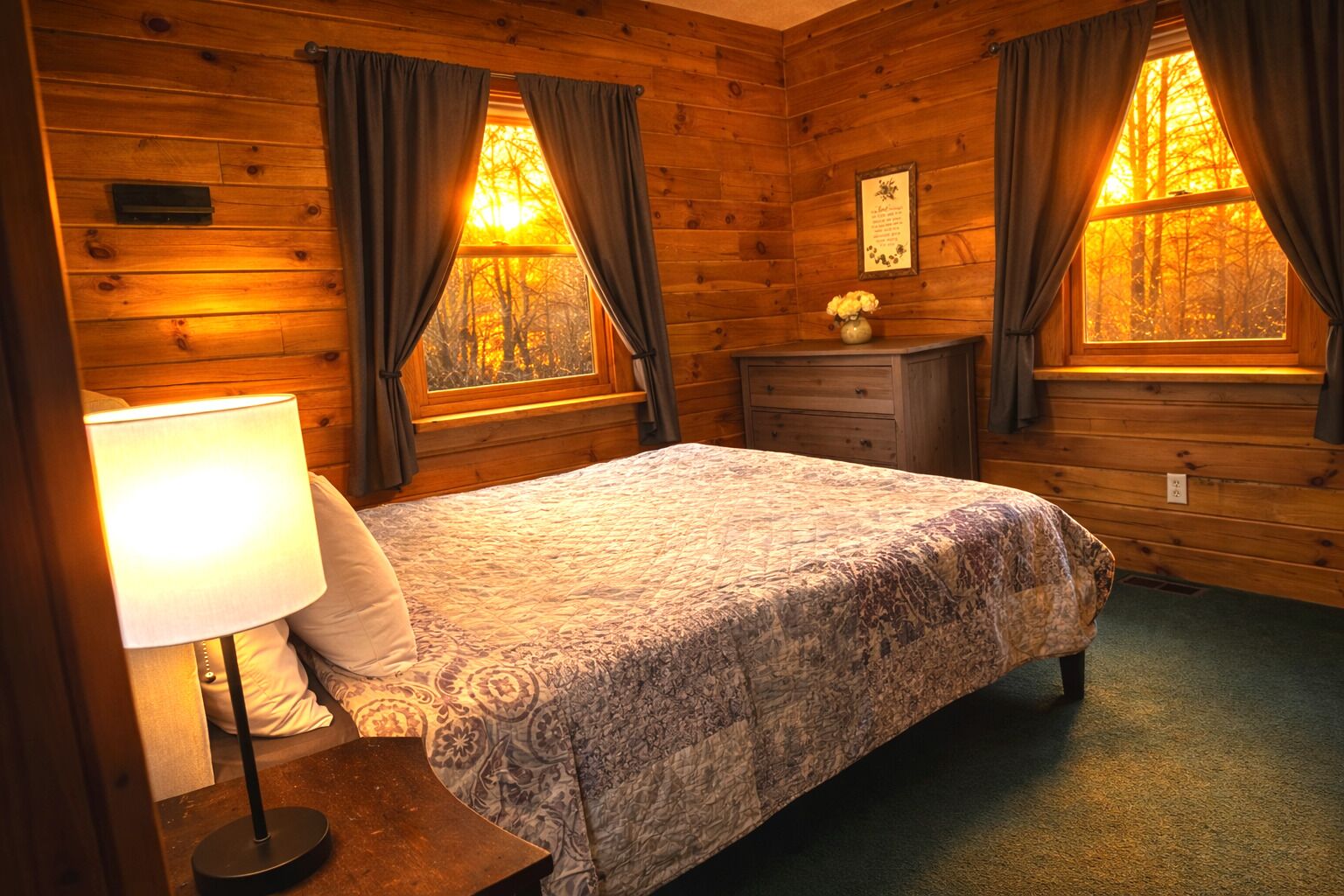 Une chambre dans un chalet en bois, avec un lit, une table de chevet, une lampe et une commode.