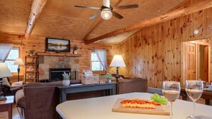 Un intérieur en bois avec une cheminée, des canapés, une table à manger avec des amuse-gueules et des verres de vin.