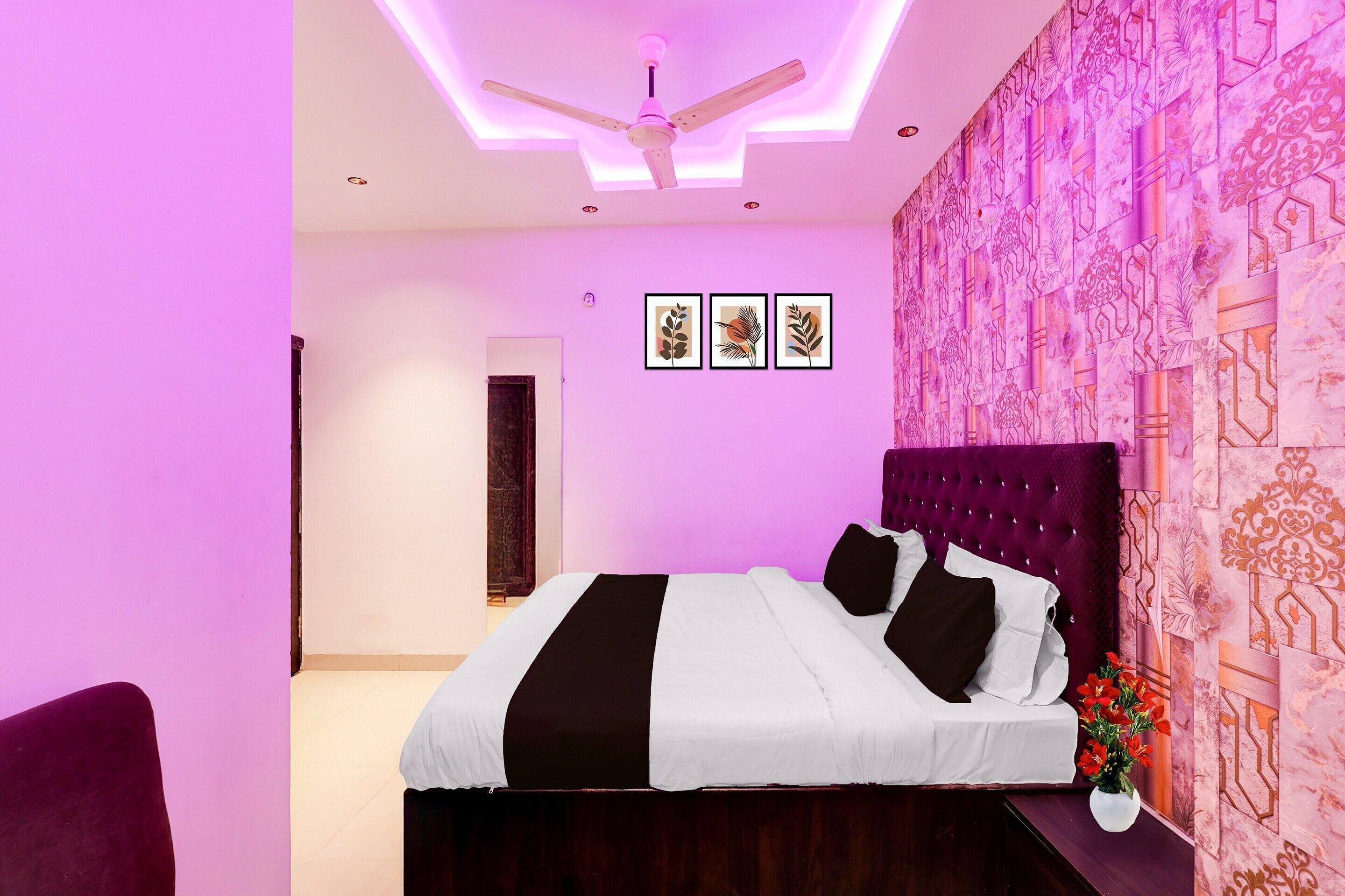 A bedroom with a bed, a ceiling fan, and a wall with patterned wallpaper.