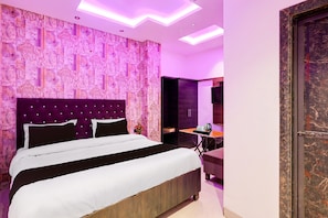 Ein modernes Hotelzimmer mit einem großen Bett, einem kleinen Tisch und einem dunkelbraunen Schrank.