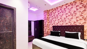 A modern bedroom with a geometric patterned wall, a tufted headboard, and a large bed. - Super Townhouse Oak Kanpur (Kanpur)