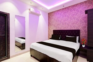 A modern hotel room with a large bed, a mirror, an air conditioning unit, and a decorative wall.