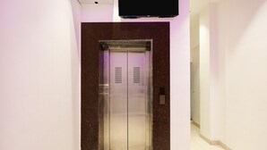 An elevator in a hallway with a flat floor and a wall-mounted television above it. - Super Townhouse Oak Kanpur (Kanpur)