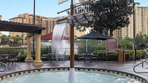 Un espace piscine agrémenté d’une fontaine, de sièges extérieurs et d’un panneau indiquant qu’il est interdit de plonger et qu’il n’y a pas de sauveteur en service.