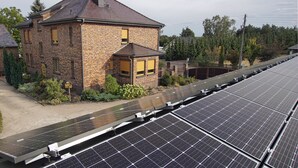Een bakstenen huis met zonnepanelen op het dak.