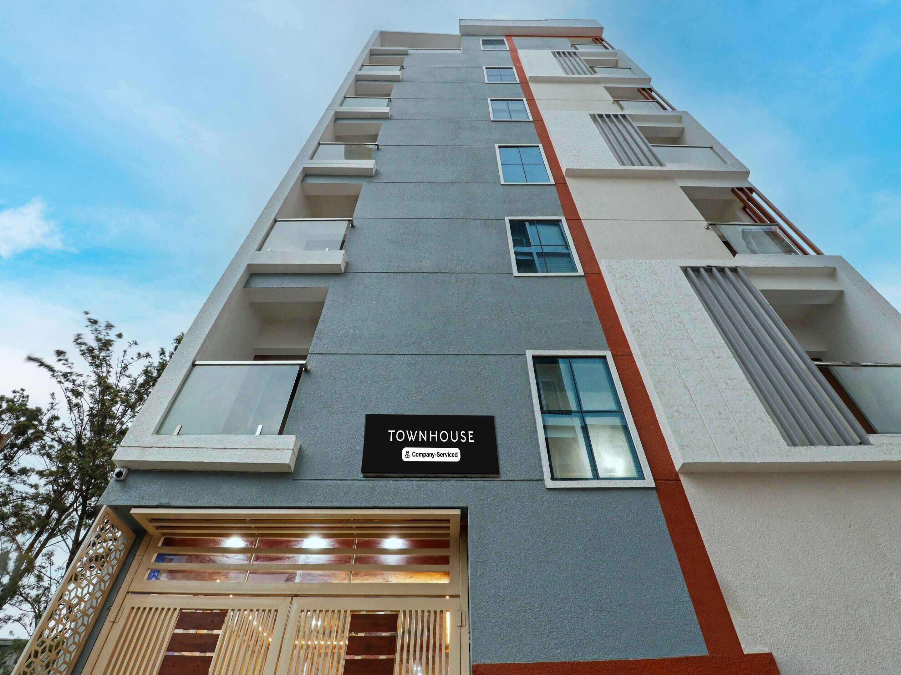 Un edificio de varios pisos con un letrero que dice 'TOWNHOUSE Company-Serviced'.