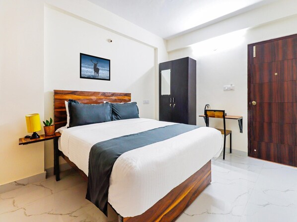 Un dormitorio ordenado con cama, mesita de noche, lámpara, planta en maceta y un armario.