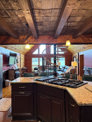 Uma cozinha espaçosa com uma ilha grande, vigas de madeira no teto e uma área de estar aconchegante com lareira.