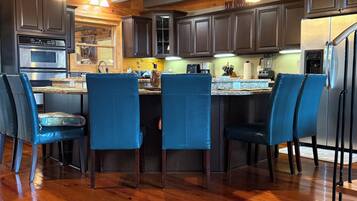 A kitchen with wooden floors, dark cabinets, and blue chairs.