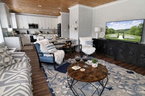 Una sala de estar moderna con un sofá, sillones, una mesa de centro y un televisor.