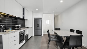 Una cocina moderna con comedor, que cuenta con una isla grande, electrodomésticos integrados y vistas a través de un ventanal.
